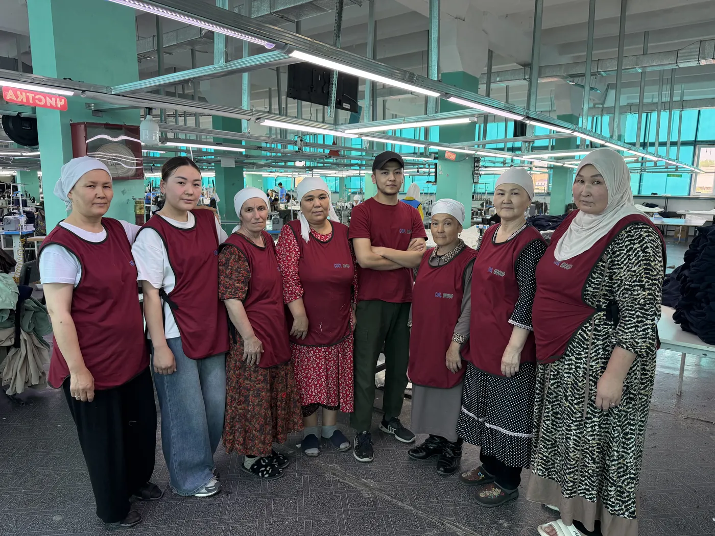 Sewing crew of the first factory on the shop floor, in burgundy work aprons