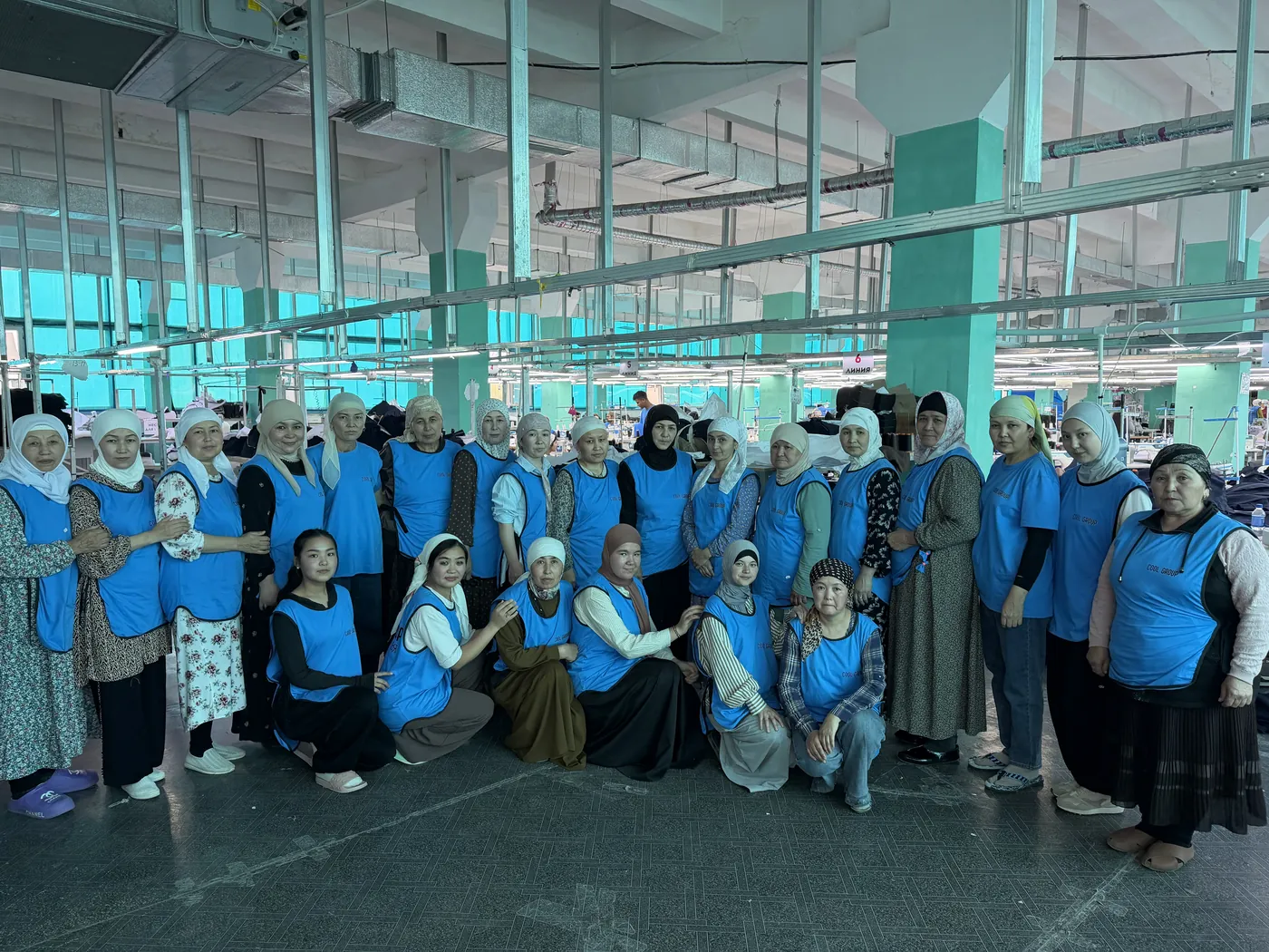 Sewing crew of the second factory gathered on the shop floor, in blue work aprons
