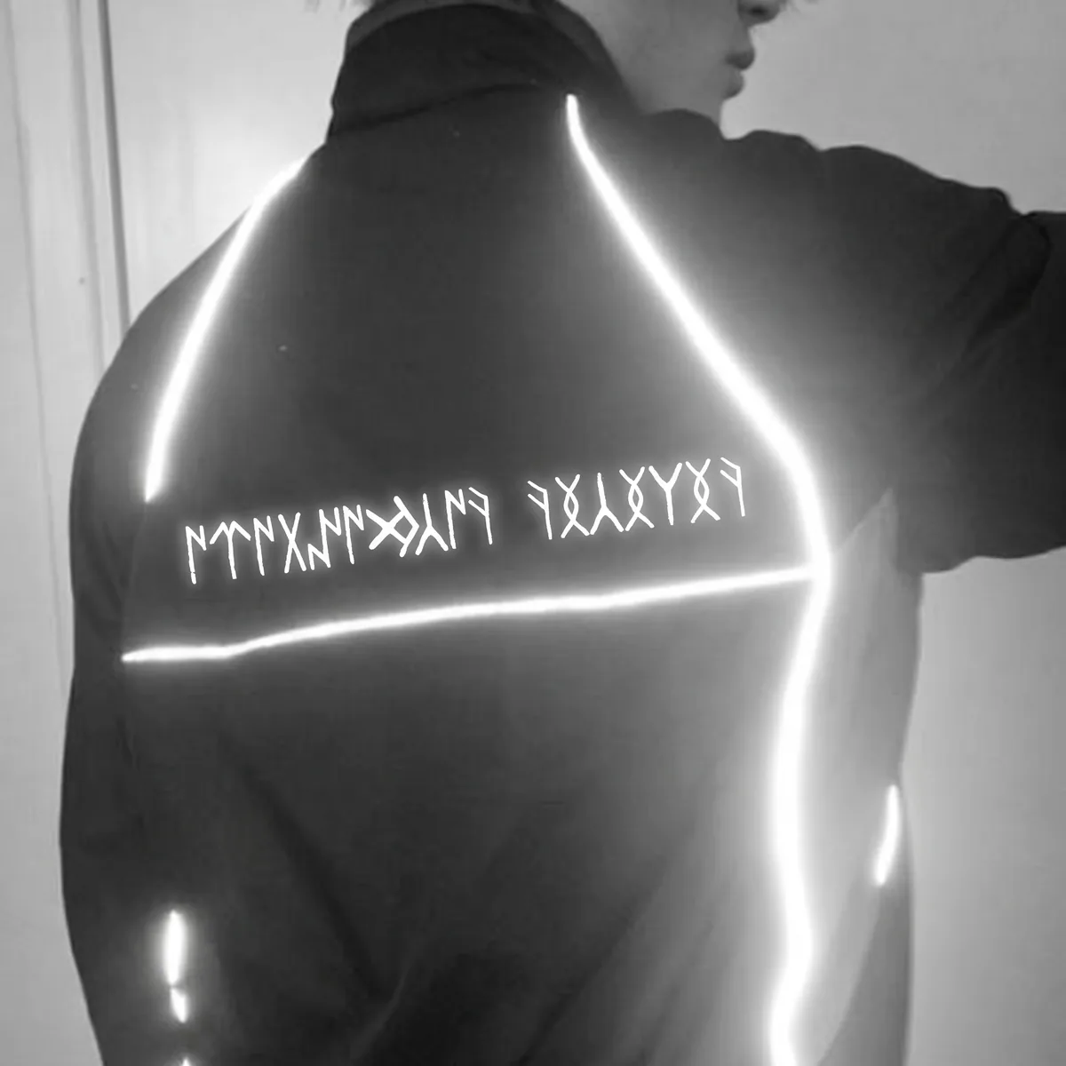 The Orkhon runic slogan lighting up white across the back of a hoodie under light