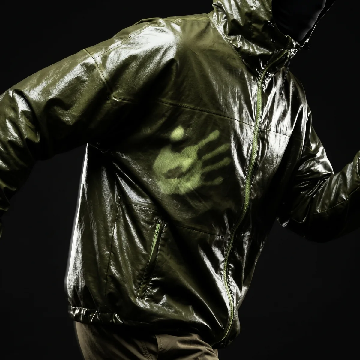 A handprint blooming lighter across the chest of a Toolor thermochromic olive shell